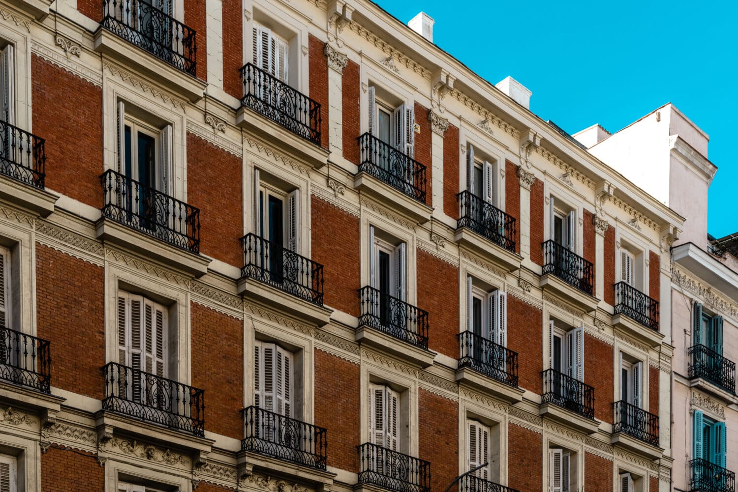 Old residential building with brick facade and iron balconies in Madrid. Rent control and real estate concept